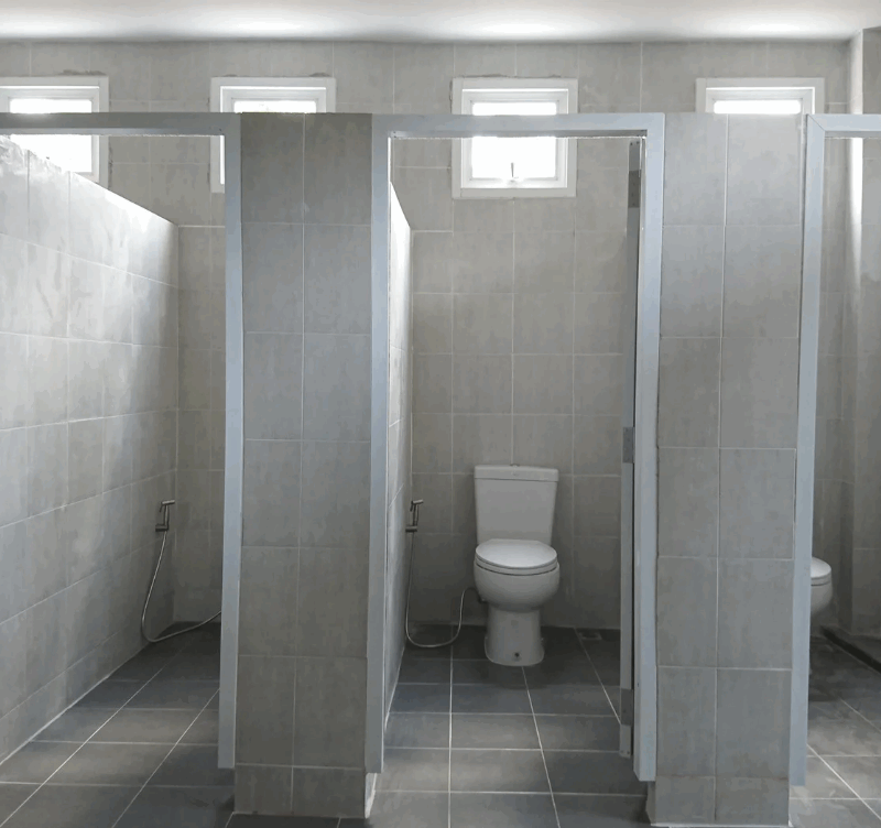 Interior view of commercial bathroom stalls, representing plumbing infrastructure in commercial buildings