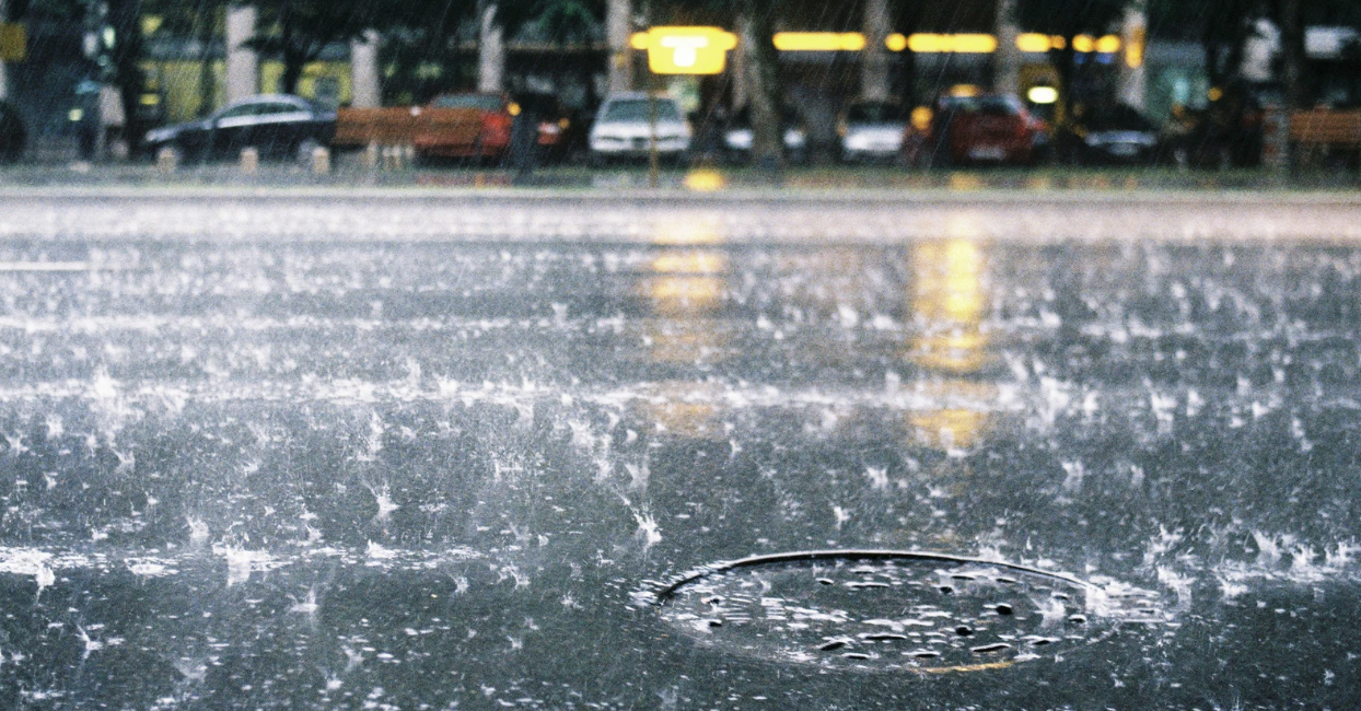 heavy rain on a street with sewer pothole